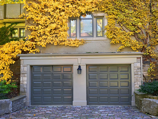 Two blue garage doors set in a building covered in yellow ivy leaves