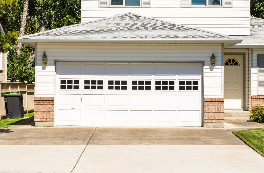Big white house with wide white garage door with small windows