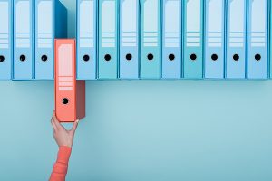 Hand pulling out a red folder from a row of blue ones