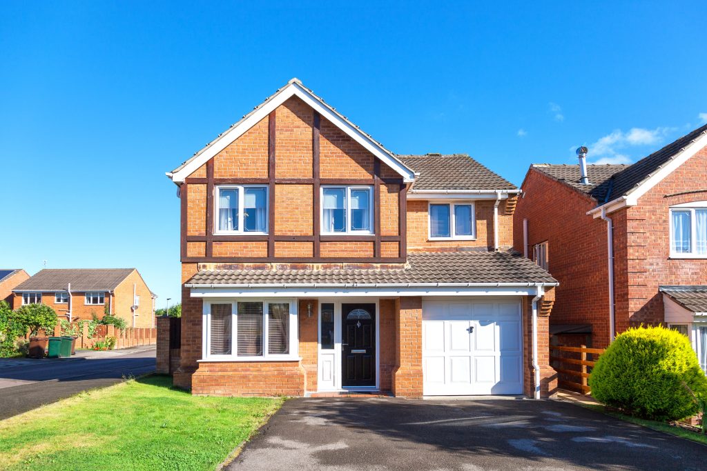 Detached house with front garden and single garage with white door