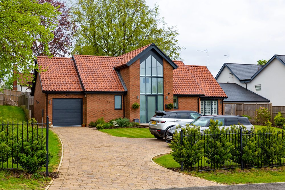 Modern detached brick house with an anthracite grey sectional garage door and block paved driveway